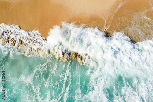 View from above, stunning aerial view of some waves crashing onto a beautiful beach during sunset. Nyang Nyang Beach (Pantai Nyang Nyang), South Bali, Indonesia.