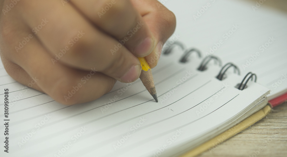 Close up of Hand and pencil writing something on notebook. Close up of Hand and pencil writing something on notebook.