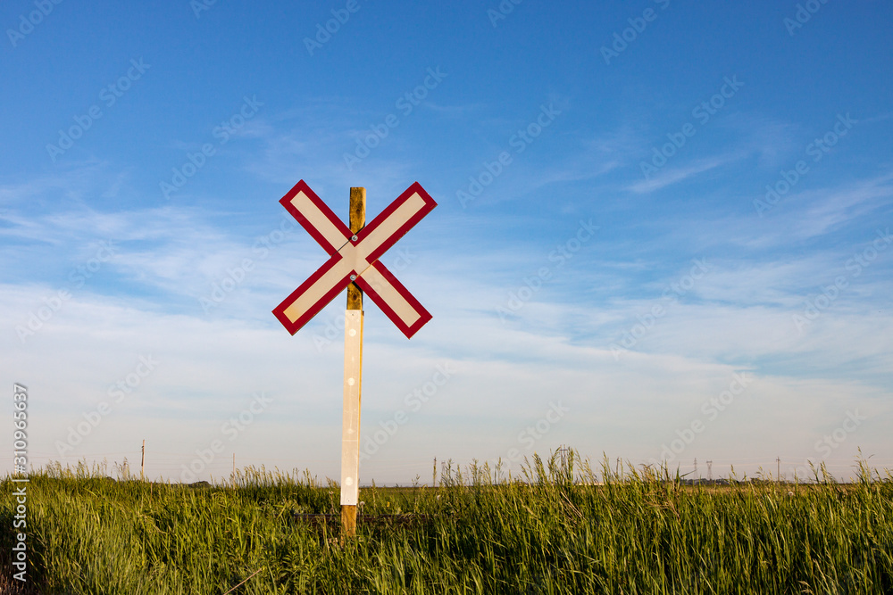 Lone Railroad Crossing Sign on Green Prairie Under Blue Summer Sky