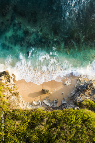 Obraz na płótnie View from above, stunning aerial view of a rocky shore with a beautiful beach bathed by a rough sea during sunset, Nyang Nyang Beach (Pantai Nyang Nyang), South Bali, Indonesia. w salonie
