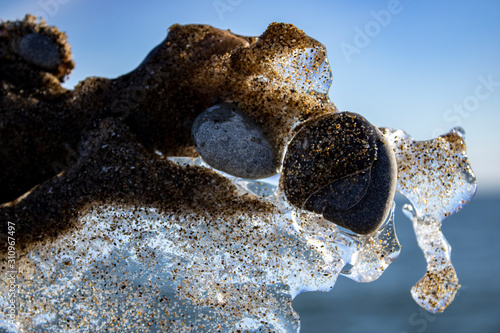 Ice shapes on the beach from rocks and pebbles in the winter photo