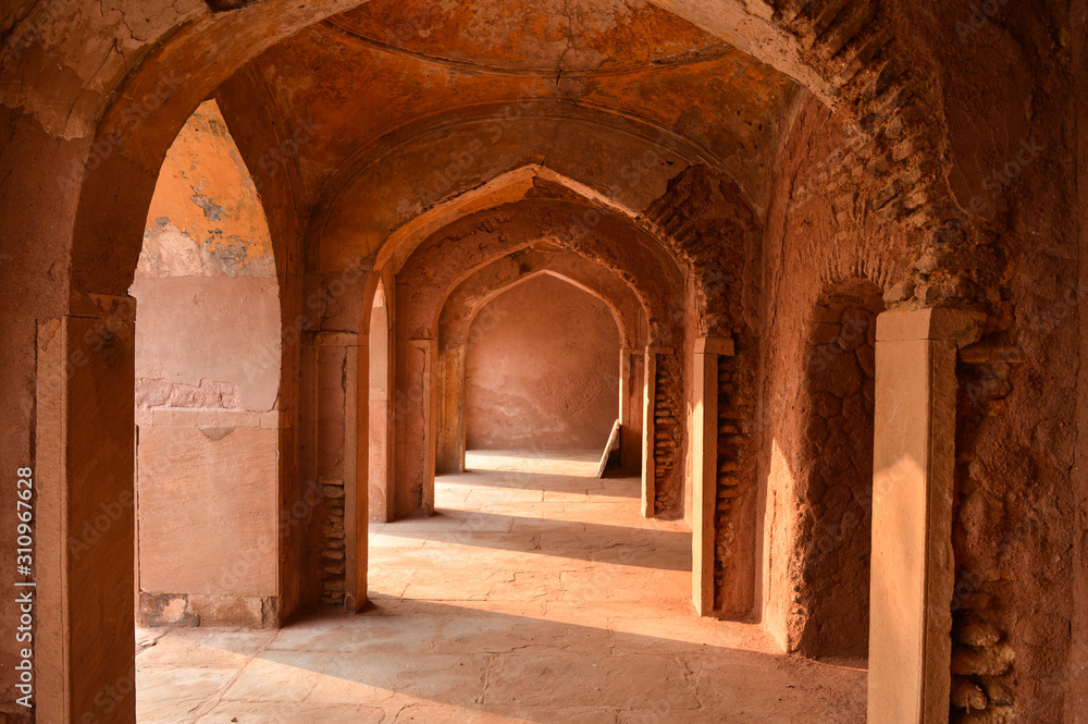 A mesmerizing view with sun rays create dramatic light and shadow of inside the hall of safdarjung tomb memorial from the main gate,entrance at winter morning.