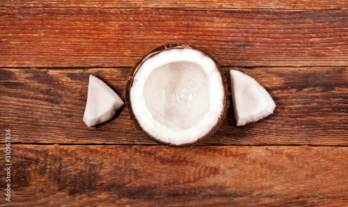 Half coconut and coconut pieces on old wooden background.