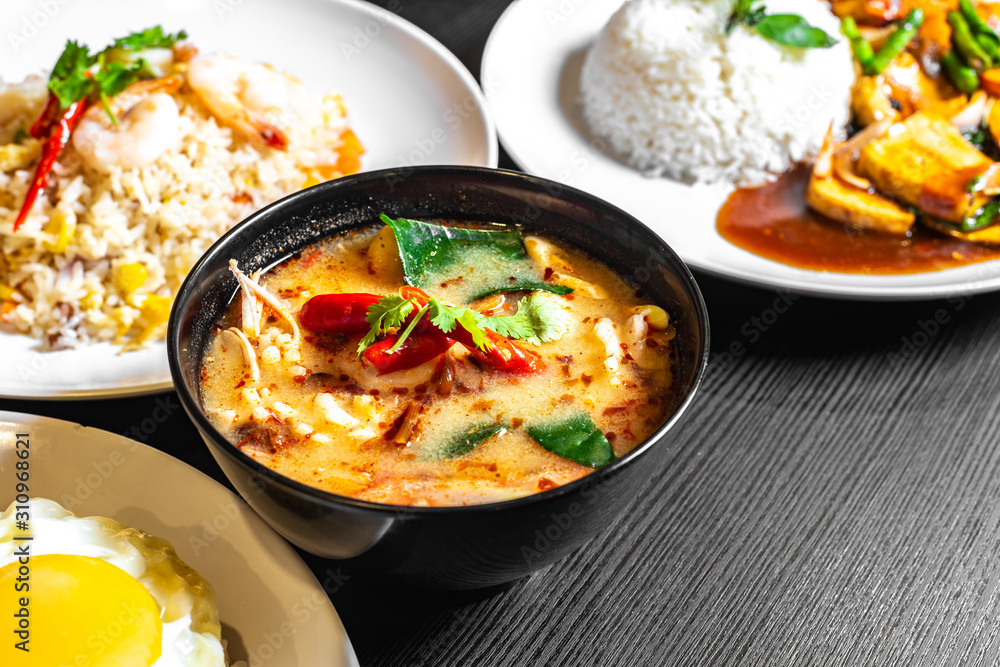 Selective focus of Thai dishes on the table. Tom yum soup, Olive fried rice, and Mixed Vegetables fried rice in the background blurred. Selective focus of Thai dishes on the table. Tom yum soup, Olive fried rice, and Mixed Vegetables fried rice in the background blurred.