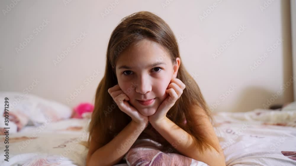 A young girl is lying and looking at the camera. Portrait of a young girl. A young girl is lying and looking at the camera. Portrait of a young girl.