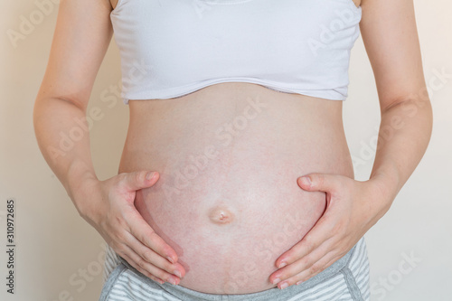 Pregnant smiling Woman caressing her belly. Mom Expecting Baby. Concept of pregnant women healthy and health care.