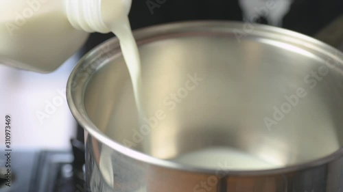 Pouring milk into a metal pot from a gallon.