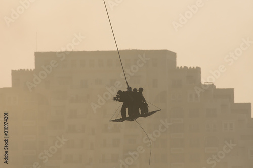 Military team in conflict resucing people by helicopter. flying through the air on a rope attached to chopper in the smoke and haze in the MIddle East conflict. photo