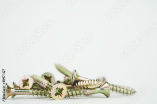 Golden tapping screws made of steel in group isolated on white background. Metal, iron, chrome, wood screws as a background. Space for copy or text. 