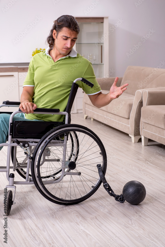 Young male invalid in wheel-chair suffering at home Young male invalid in wheel-chair suffering at home