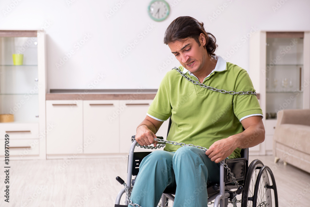 Young male invalid in wheel-chair suffering at home Young male invalid in wheel-chair suffering at home