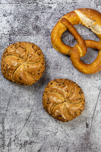 Multicereal seed buns and pretzel on a concrete background