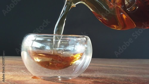 Hot tea in a clear glass on piece of wood and steam from the glass