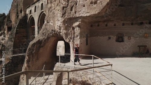 Tourist blonde caucasian female walking in cave city complex and looking around