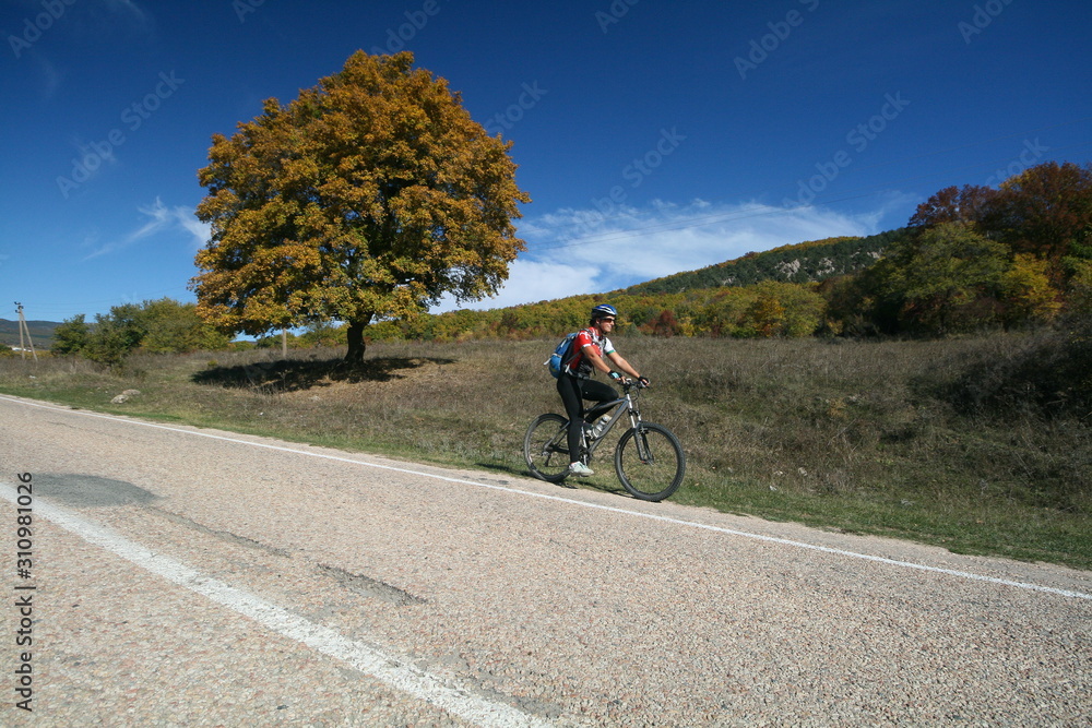 A young woman on a Bicycle rides on autumn road, Crimea, Russia