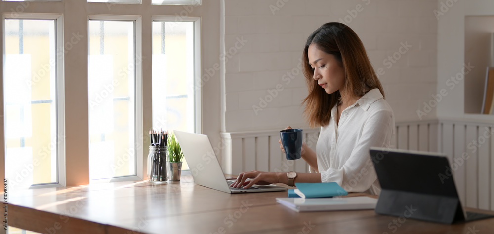 Young professional businesswoman working on her project while drinking a cup of coffee Young professional businesswoman working on her project while drinking a cup of coffee