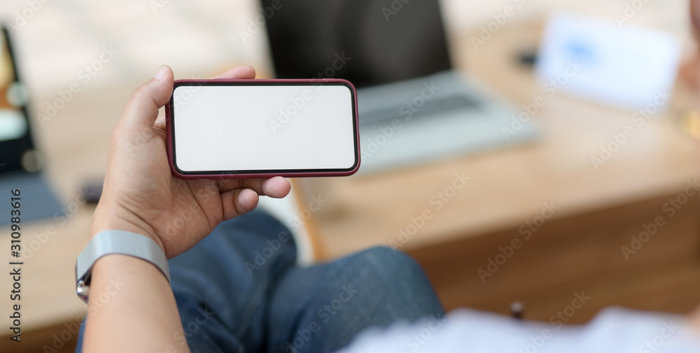 Cropped shot of man holding blank screen smartphone while sitting in comfortable workplace Cropped shot of man holding blank screen smartphone while sitting in comfortable workplace
