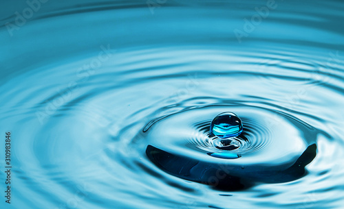 Closeup Water drop falling on the surface of the water and beautiful circular wave ripple, fresh natural mineral water drink water concept