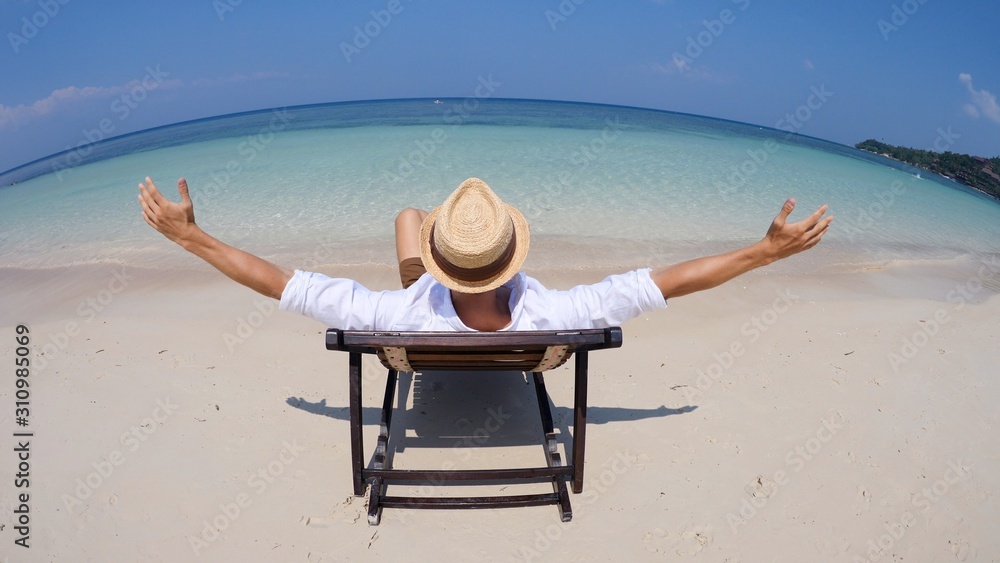 Man Raising Arms Relaxing In Deck Chair On Beach On Holiday