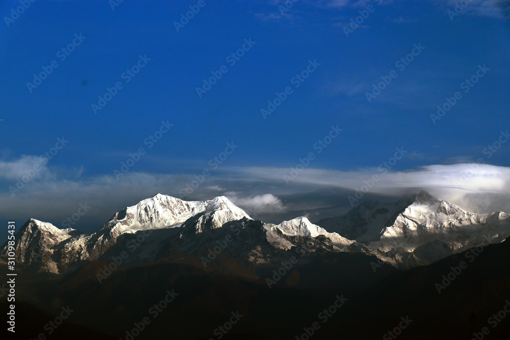 Kanchanjungha during golden hour, snow, peak, landscape, nature, Himalayan. Snowy mountains of Himalaya. A beautiful snowy mountain landscape under a blue cloudy sky..