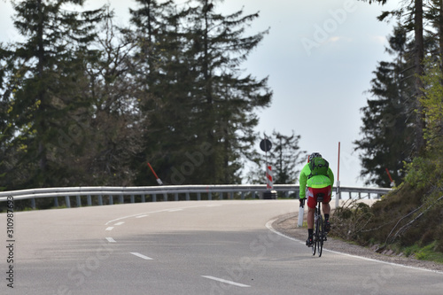 Schwarzwald  Germany - April 25 2019  Highway through the forest and a cyclist in a green jacket with a backpack and helmet