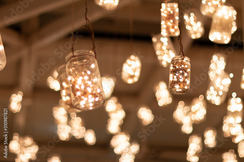 Jars hanging from the ceiling of the bar with warm led lights inside.