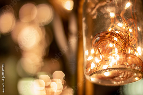 Hanging jars with warm led lights inside and some bokeh in background.