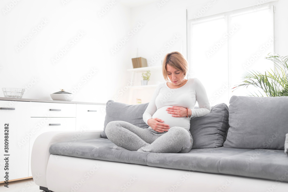 Pregnant tired exhausted woman with stomach and head issues at home on a couch, being sick. Pregnant tired exhausted woman with stomach and head issues at home on a couch, being sick.