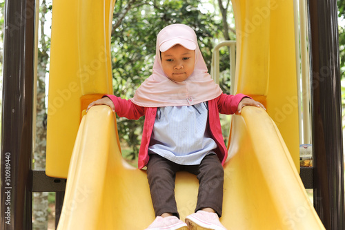 Little cute girl playing on the slide at outdoor. Cute girl playing on slide on weekend