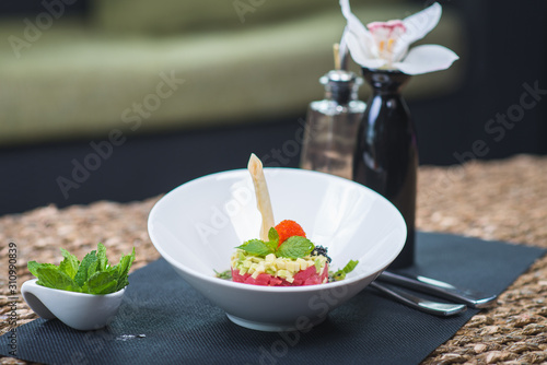Classic traditional tartar salad laid in a round shape, stylish serving in an oriental style table in a restaurant. Tasty and healthy food. Guests service. Tar tar on a stylish plate with decor.