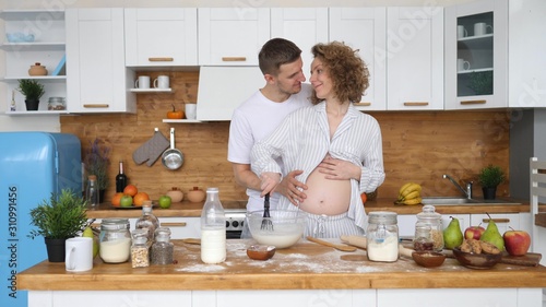 Pregnant Woman With Husband Cooking Together In Kitchen