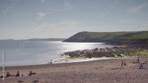 Wide high angle sunny day panoramic still shot of a reservoir beach landscape, reflections, and summer tourists relaxing, Foremark, Derbyshire, UK photo