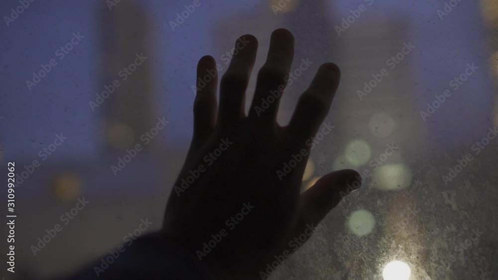 Hand touching glass with the city lights in background Hand touching glass with the city lights in background