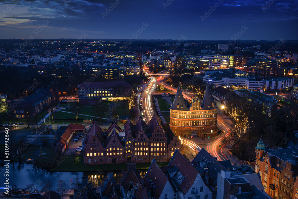 Obraz Aerial night view of the illuminated city of Luebeck, Germany in winter with Holstentor and historic Salzspeicher houses, long term exposure at blue hour, copy space