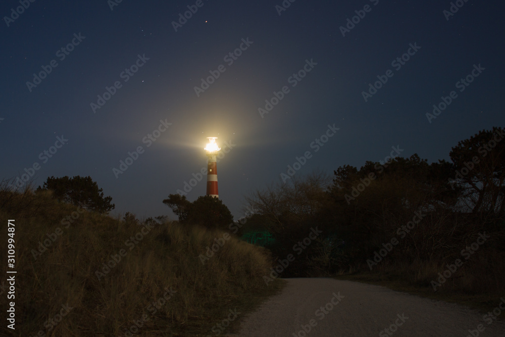 vuurtoren light house on ameland at night with lights and stars in the sky