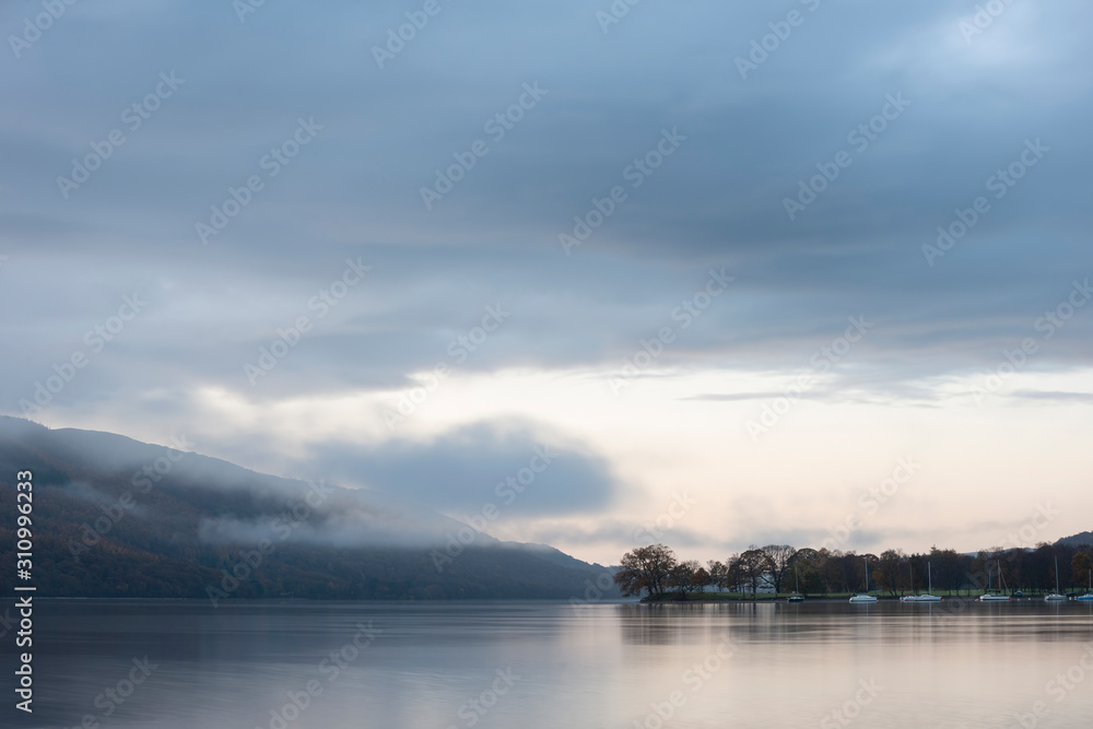 Stuning Autumn Fall sunrise landscape over Coniston Water with mist and wispy clouds Stuning Autumn Fall sunrise landscape over Coniston Water with mist and wispy clouds