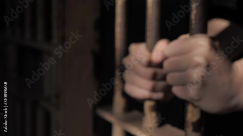 Hands holding prison jail gaol cell bars Woman locked behind bars