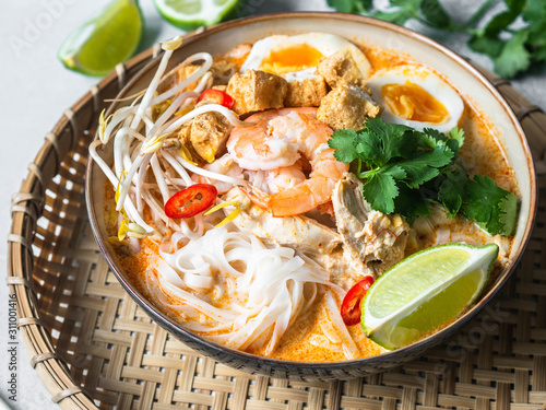 Canvas Print Malaysian noodles laksa soup with chicken, prawn and tofu in a bowl on grey back
