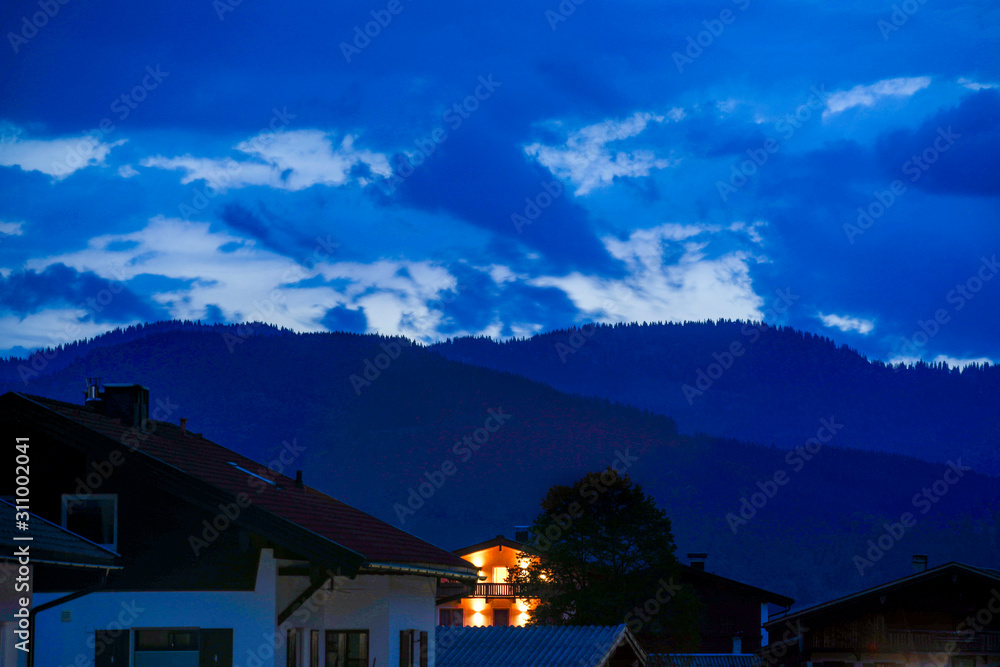 Rot Beleuchtete Hütte umrahmt von dunklen Bergen im Hintergrund - Blauestunde Sonnenuntergang