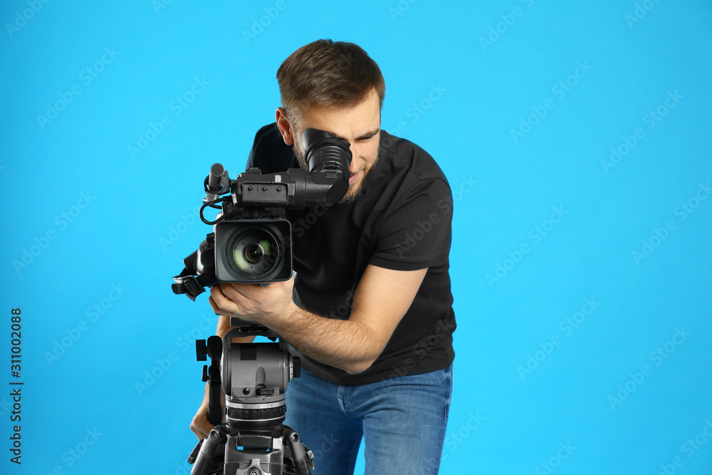 Operator with professional video camera on blue background Operator with professional video camera on blue background