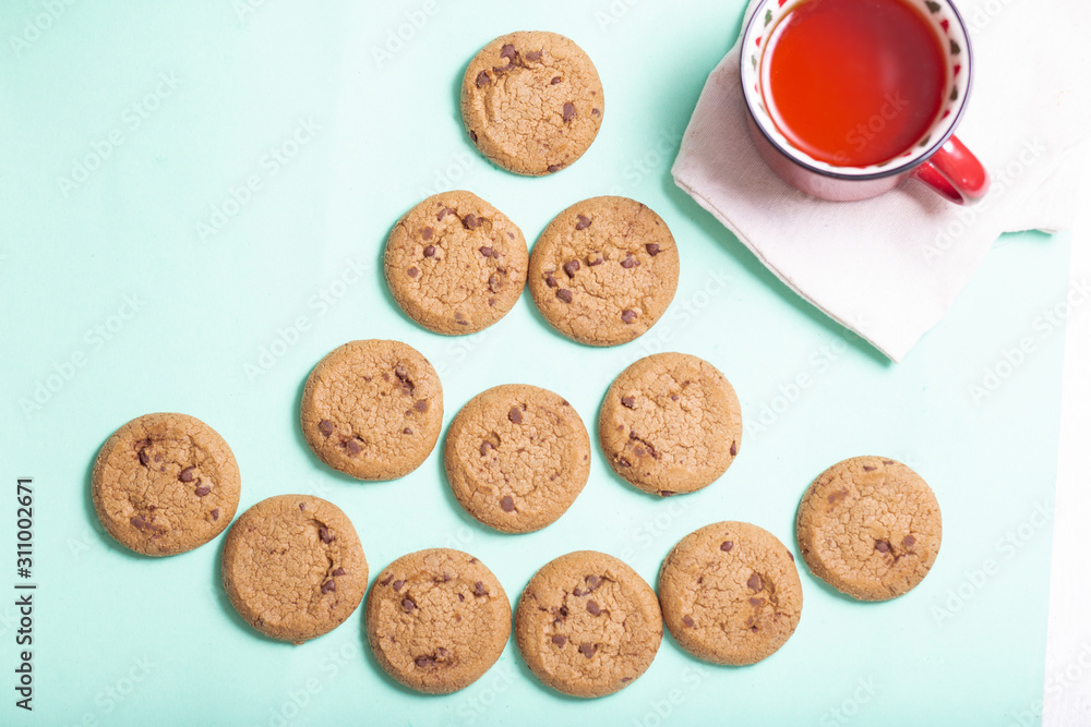 homemade cookies lies in the form of a Christmas tree and a mug of strong tea on a light background, top view homemade cookies lies in the form of a Christmas tree and a mug of strong tea on a light background, top view