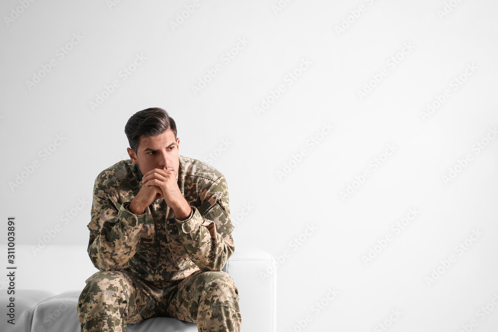 Obraz premium Stressed military officer sitting on sofa against white background. Space for text