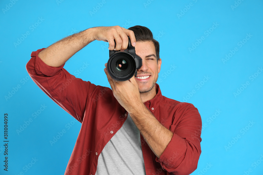 Fototapeta premium Professional photographer working on light blue background in studio