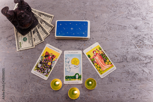 Divination cards alignment with black Buddha statue, money banknotes and candles. Mystery, astrology, fortune telling, belief, prosperity and wealth concept.