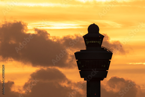 Photography Amsterdam Schiphol International Airport control tower with a plane landing in the background during sunset