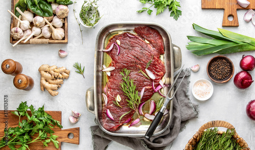 Raw flank steak marinated in a spicy mix with herbs, top down view