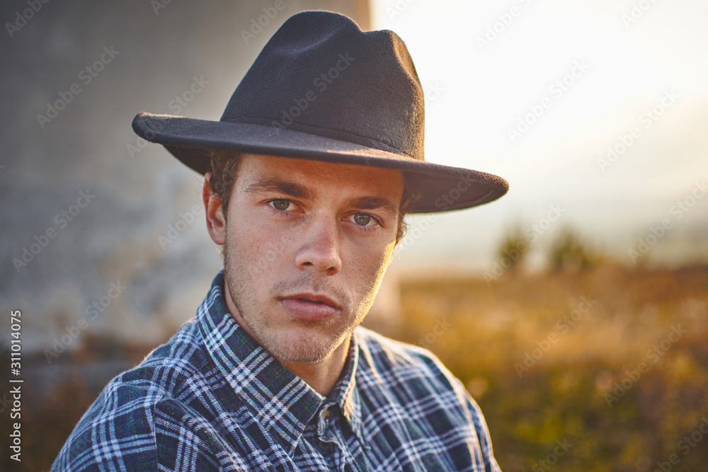 Portrait of western young handsome farmer at sunset looking satisfied with his work 