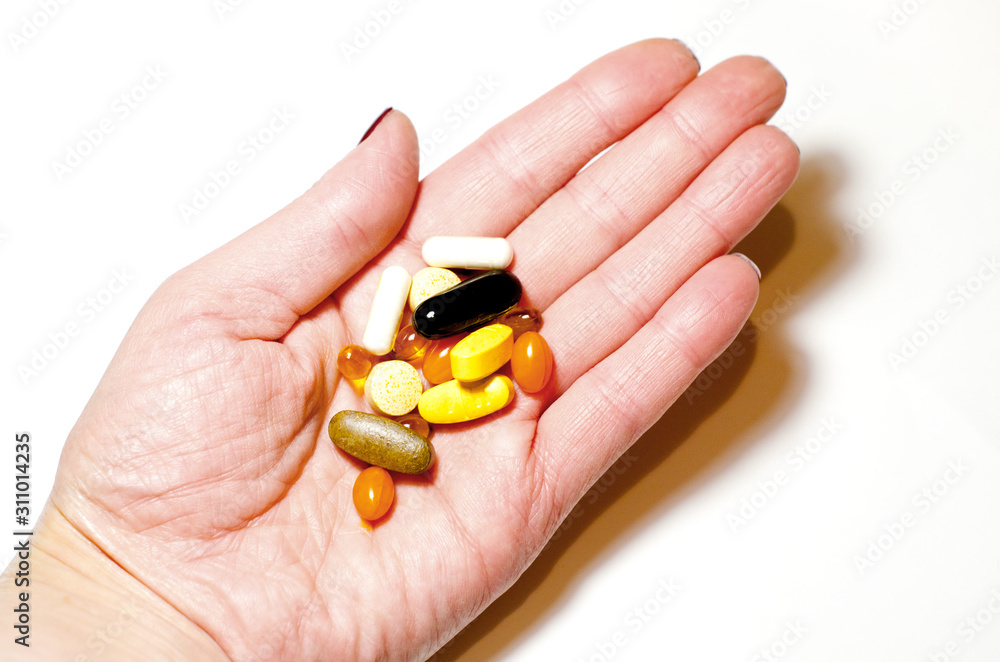 Capsules and tablets of different colors and shapes are a handful in the palm of your hand on a white background. Vitamins, Sports nutrition. Top view, close-up, selective focus. Capsules and tablets of different colors and shapes are a handful in the palm of your hand on a white background. Vitamins, Sports nutrition. Top view, close-up, selective focus.
