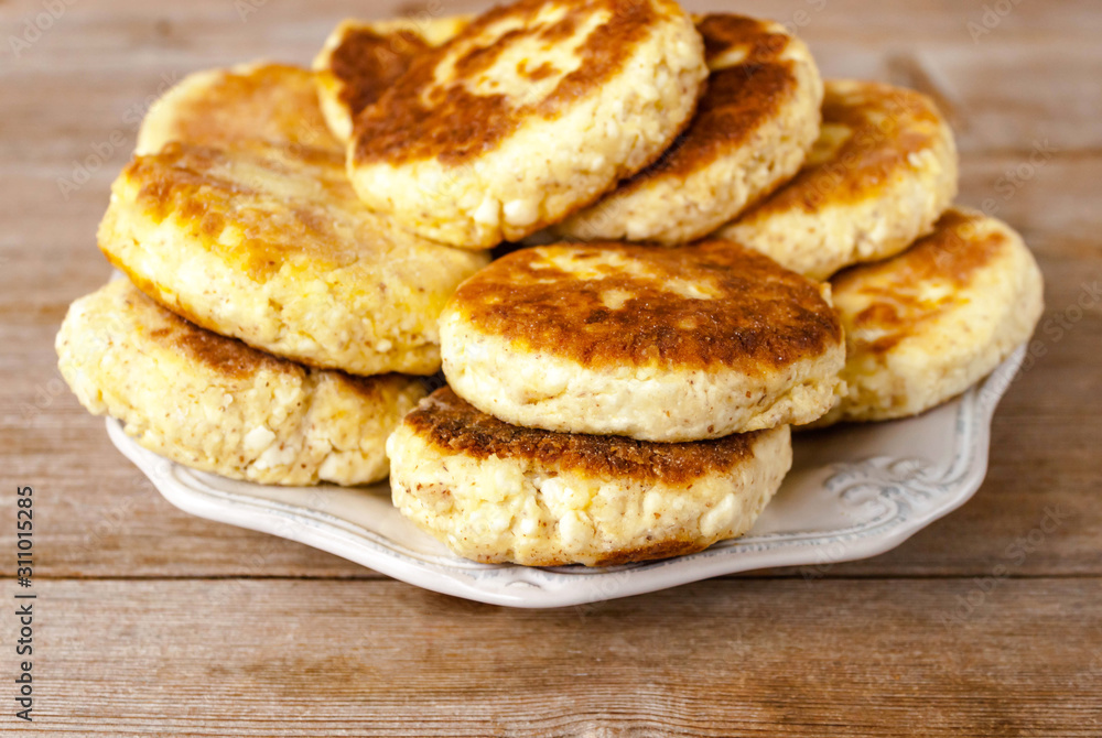 Russian traditional syrniki cottage cheese pancakes breakfast on the plate on wooden background
