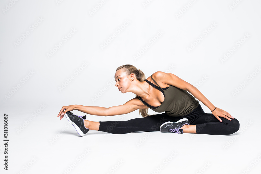 Fit sport woman stretching her leg to warm up isolated over white background Fit sport woman stretching her leg to warm up isolated over white background